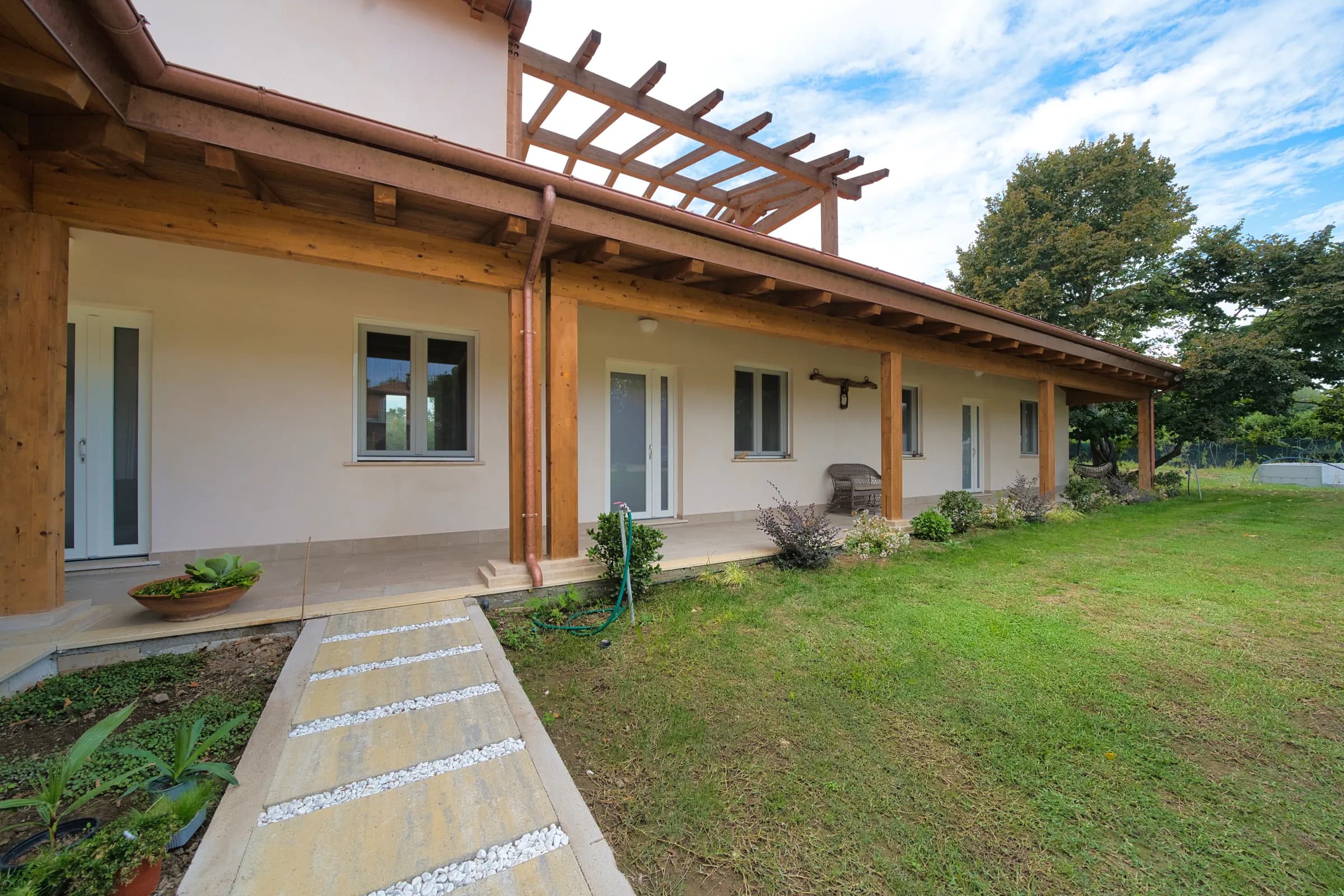 Il portico in legno davanti alle camere, con il vialetto nel giardino